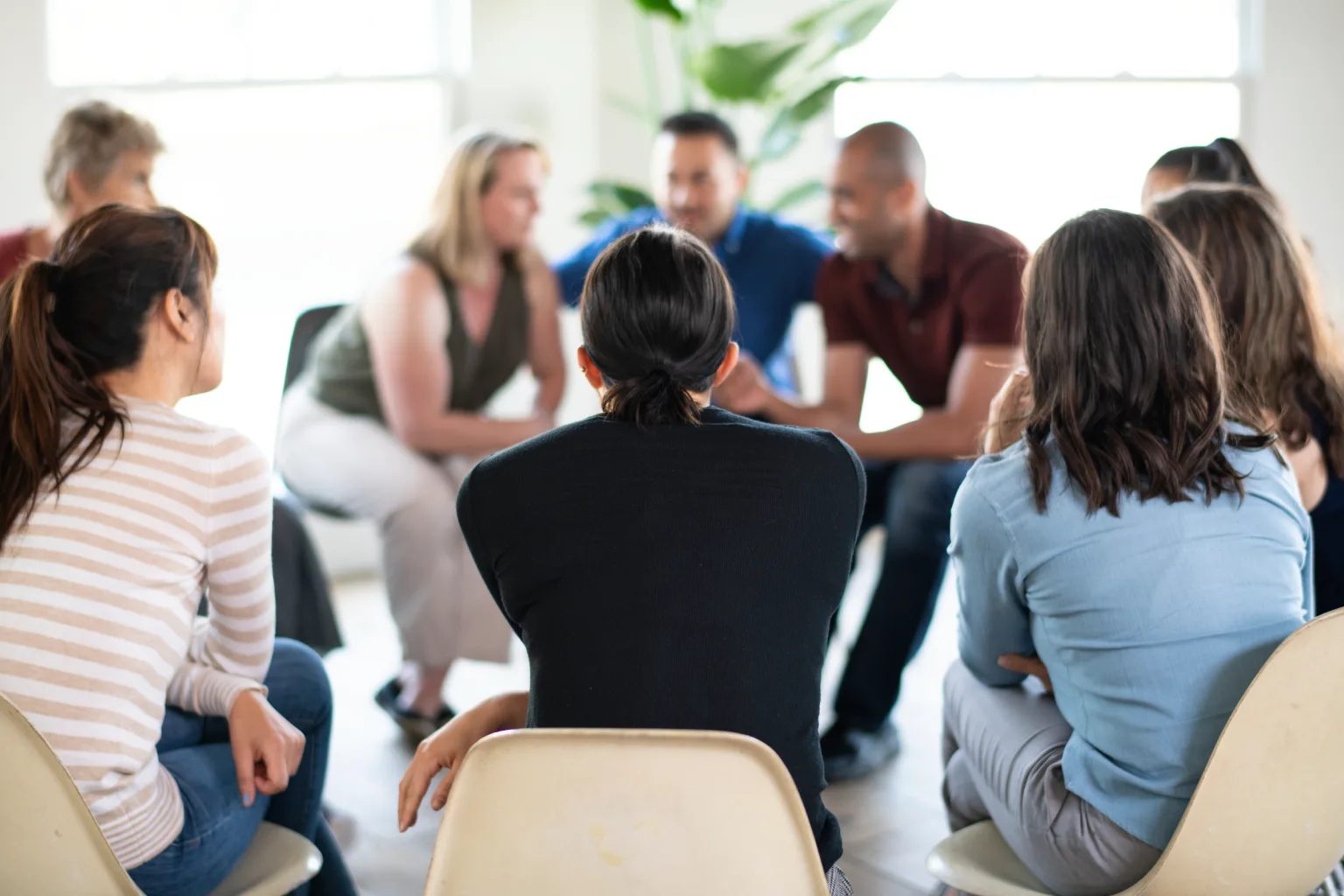 Grupo diverso de personas participando en una sesión de discusión en círculo, enfatizando la colaboración y el apoyo mutuo en un entorno acogedor.